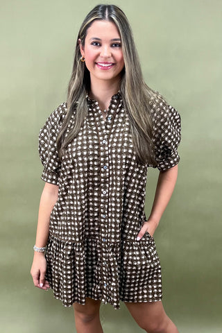 Woman wearing a brown and white polka dot dress against a green background