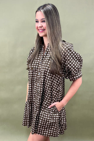 Woman wearing a patterned dress against a plain background