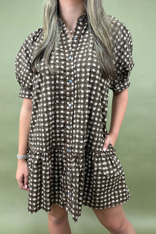 Person wearing a patterned dress against a green background