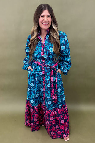 Woman wearing a blue and pink floral dress against a green background