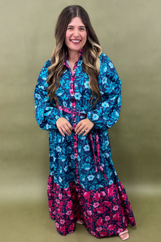 Woman wearing a blue and pink floral dress against a green background