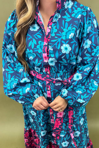 Woman wearing a blue floral dress with pink accents on a beige background