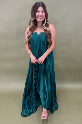 Woman wearing a teal dress against a plain background