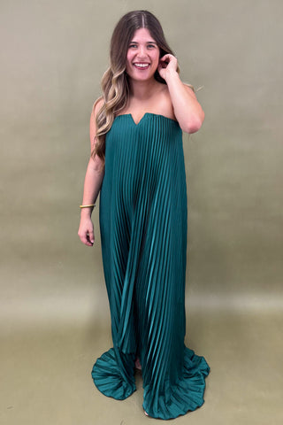 Woman wearing a teal strapless dress against a plain background