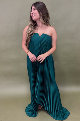 Woman wearing a teal strapless gown against a plain background