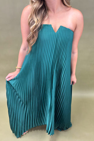 Teal pleated dress worn by a person on a beige background