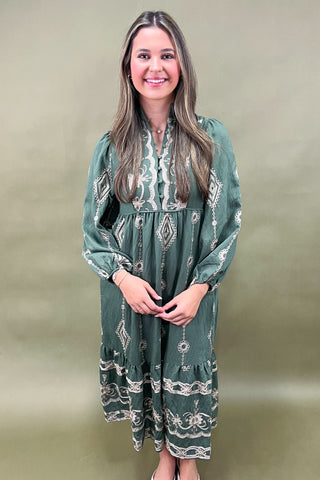 Woman wearing a green patterned dress against a plain background