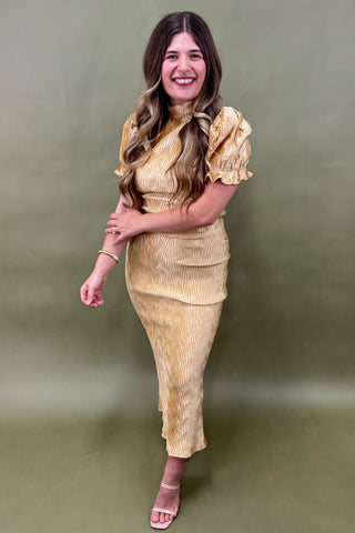 Woman wearing a gold dress against a green background