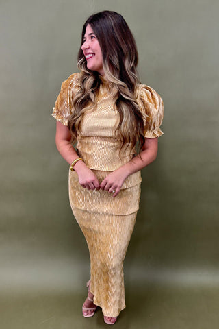 Woman wearing a gold outfit against a green background