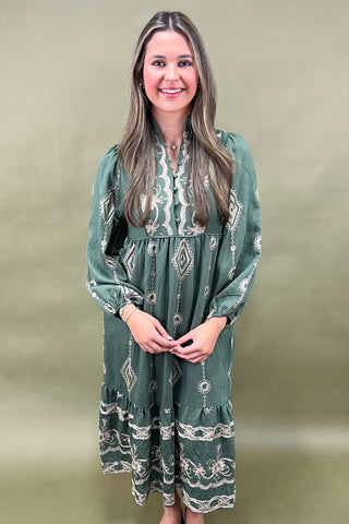 Woman wearing a green patterned dress against a plain background