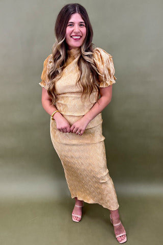 Woman wearing a gold dress against a green background
