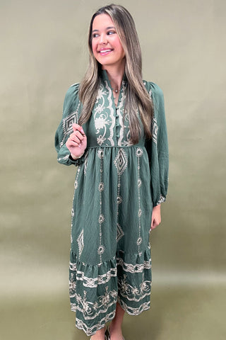 Woman wearing a green dress with white patterns against a beige background