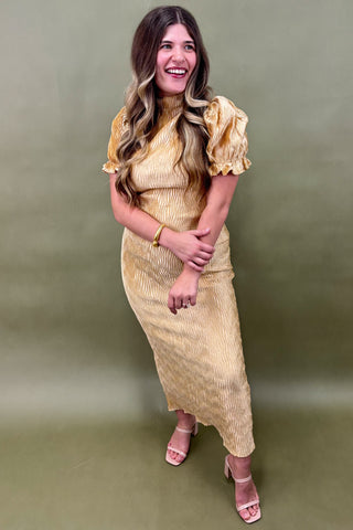 Woman wearing a gold dress against a green background