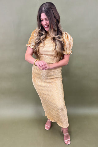 Woman wearing a gold dress against a green background