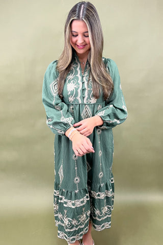 Woman wearing a green patterned dress against a beige background