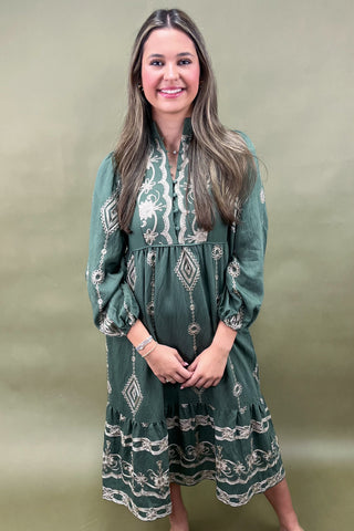 Woman wearing a green dress with white patterns against a beige background