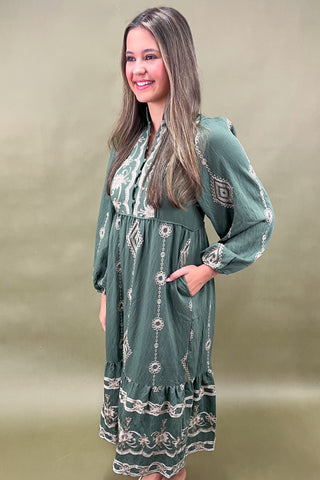 Woman wearing a green dress with white patterns against a beige background