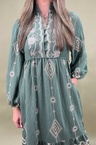 Green dress with intricate patterns worn by a person against a neutral background