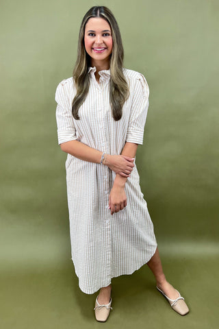 Woman wearing a white dress with vertical stripes against a green background
