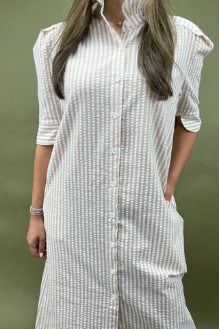 Person wearing a white and gray striped shirt with short sleeves against a green background