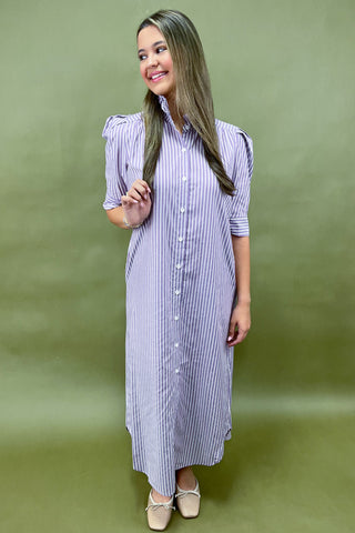 Woman wearing a blue and white striped dress against a green background