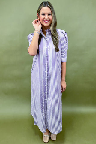 Woman wearing a long, striped dress against a green background