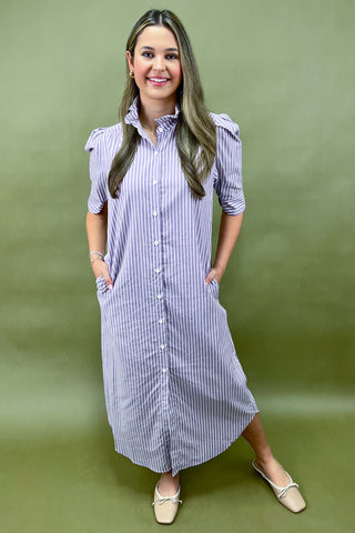 Woman wearing a blue and white striped dress against a green background