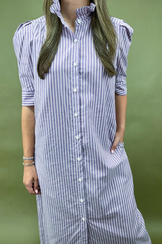 Person wearing a long, striped shirt dress against a green background