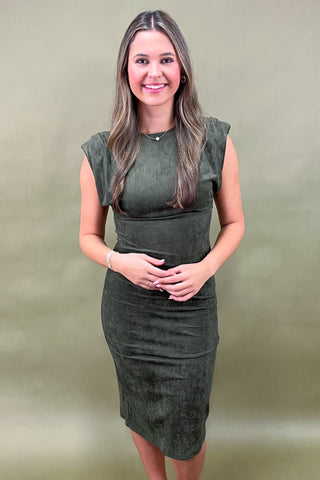 Woman wearing a green dress against a beige background