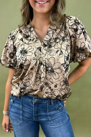 Woman wearing a floral blouse and blue jeans against a green background