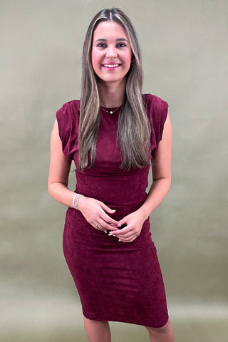 Woman wearing a burgundy dress against a plain background