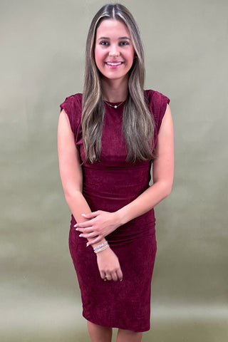 Woman wearing a burgundy dress against a plain background
