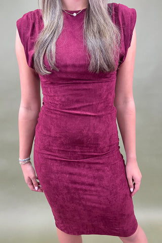 Person wearing a burgundy dress against a plain background