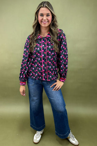 Woman wearing a patterned jacket and jeans on a green background