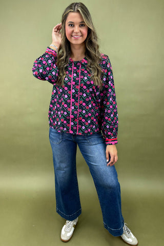 Woman wearing a colorful patterned jacket and blue jeans on a green background