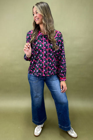 Woman wearing a patterned jacket and jeans on a green background