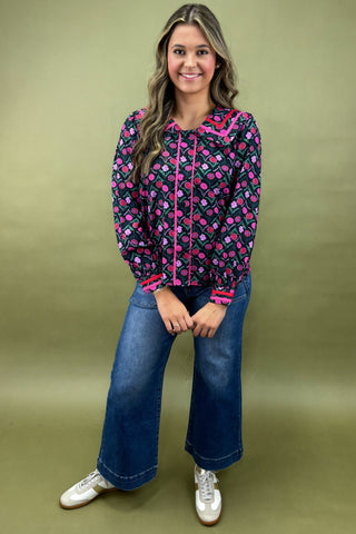 Woman wearing a patterned jacket and jeans on a green background