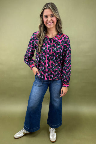 Woman wearing a colorful patterned jacket and blue jeans on a green background