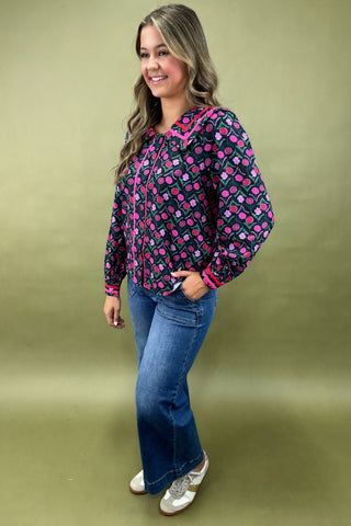 Woman wearing a patterned blouse and jeans on a green background