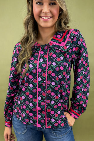 Woman wearing a floral patterned blouse with pink accents on a green background