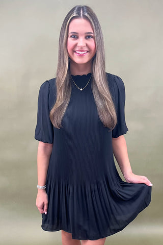 Woman wearing a black dress against a plain background