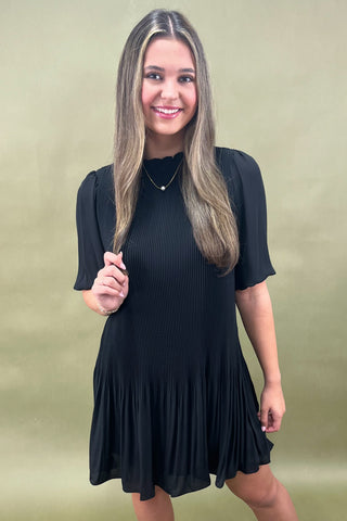 Woman wearing a black dress against a beige background