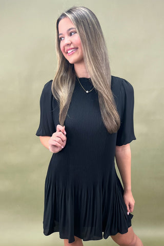 Woman wearing a black dress against a beige background