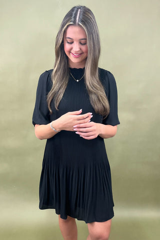 Woman wearing a black dress against a green background