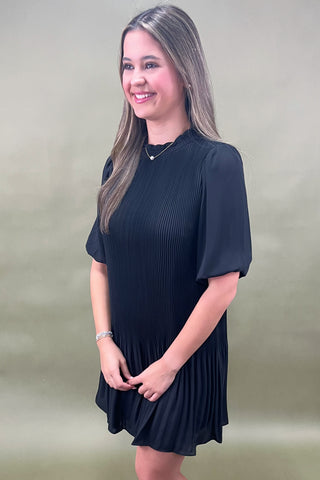 Woman wearing a black dress against a plain background