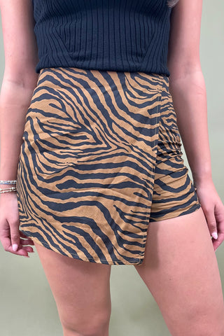 Person wearing a navy top and zebra print shorts against a neutral background
