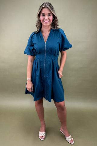Woman wearing a blue dress against a green background