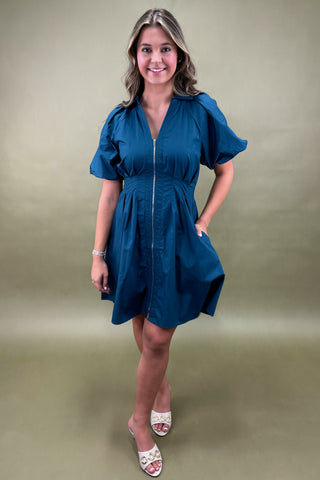 Woman wearing a blue dress against a green background