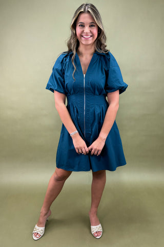 Woman wearing a blue dress against a green background