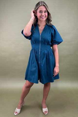 Woman wearing a blue dress against a green background